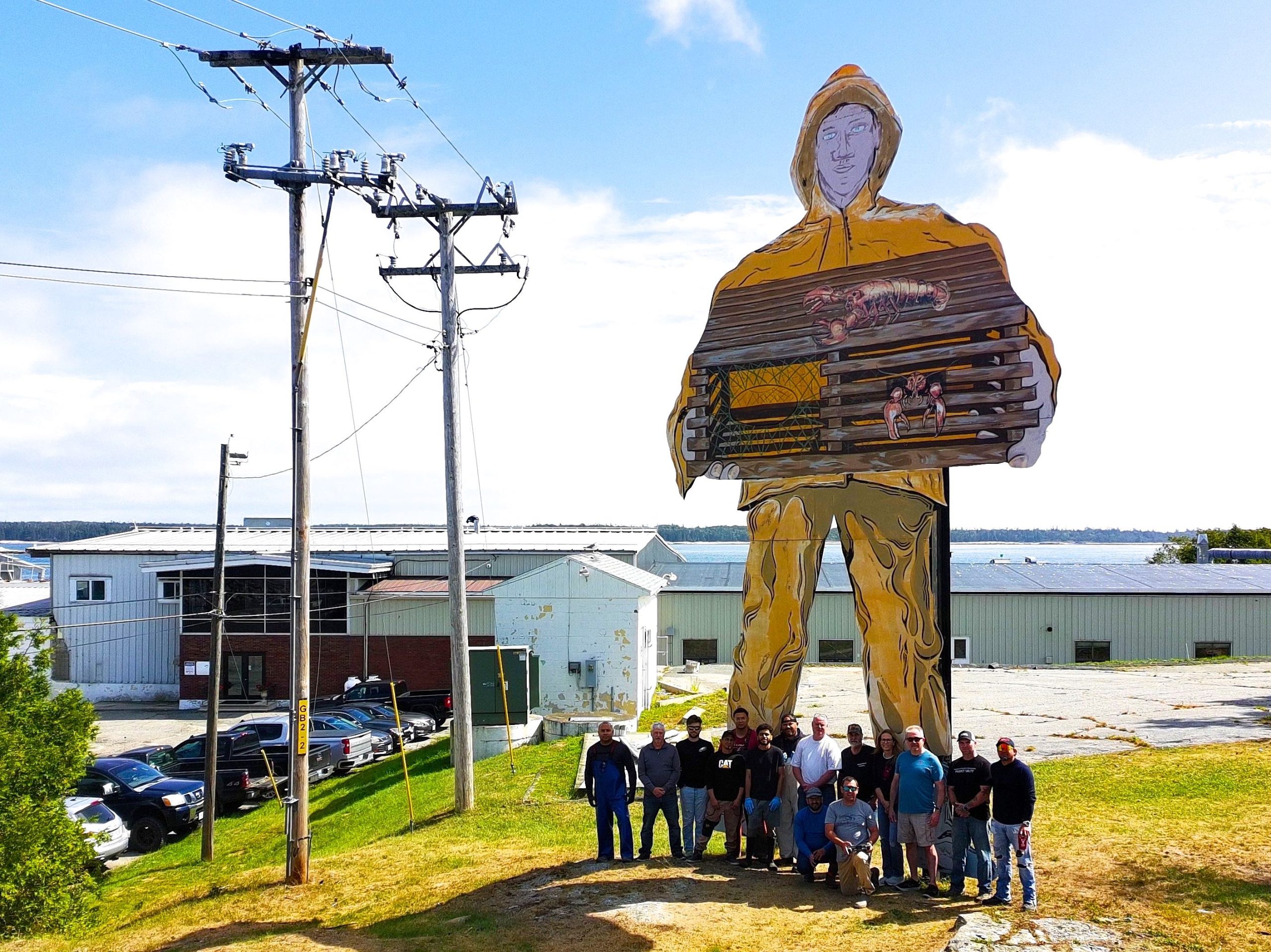 People stand in a line in front of a big statue.