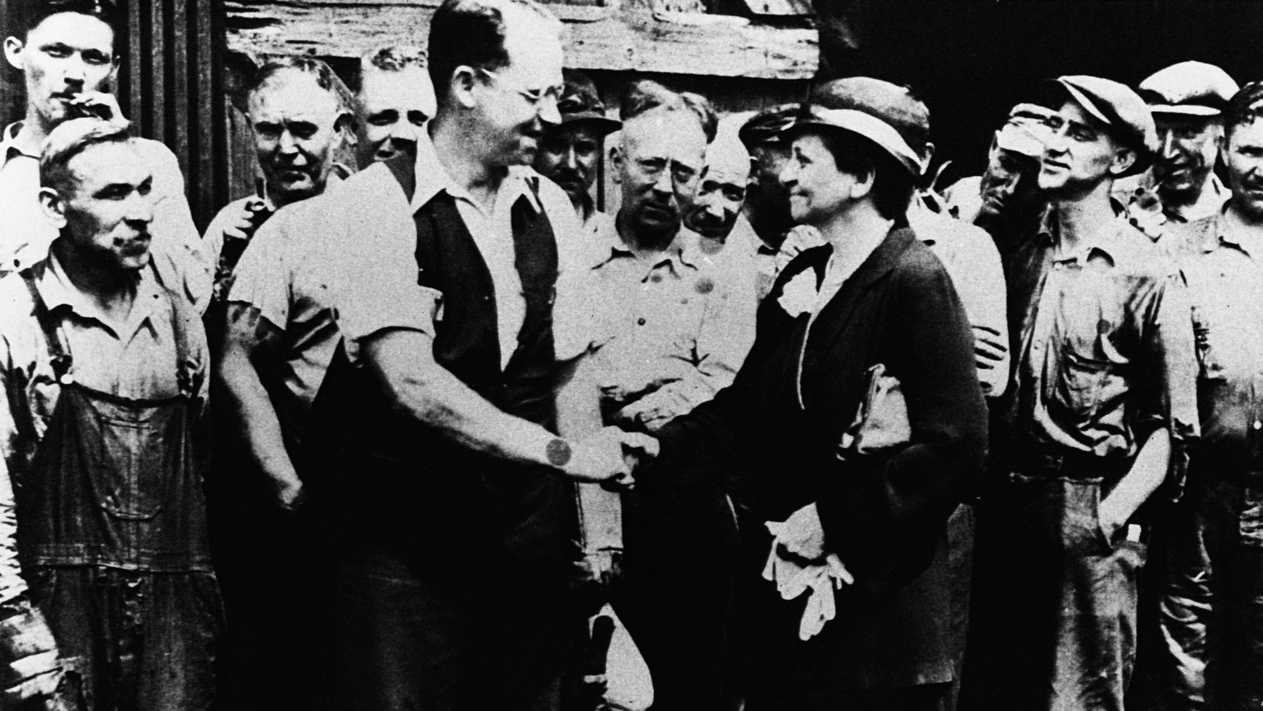 A black-and-white photo shows people shaking hands.