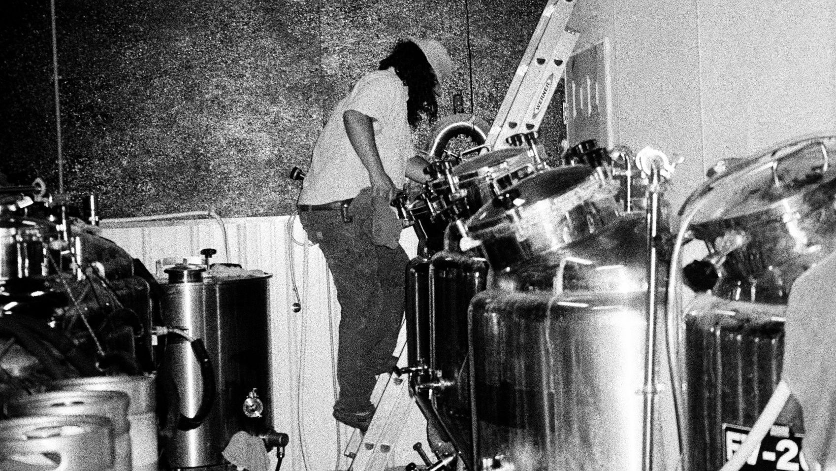 A person works with brew tanks.