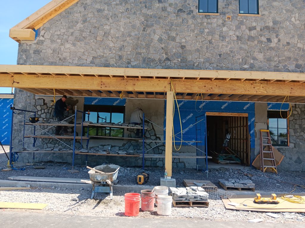 two masons affixing stone facade to building