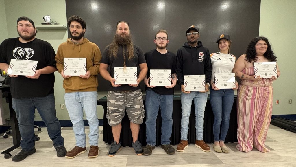 People pose in a line holding certificates.