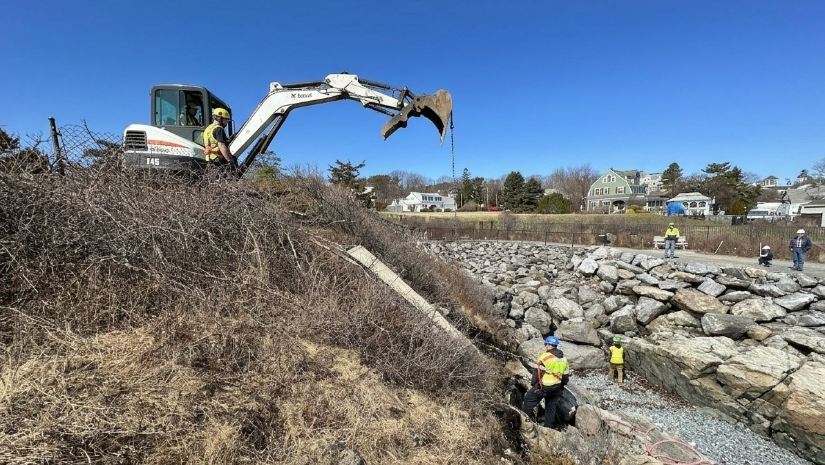 An excavator works near the shore.